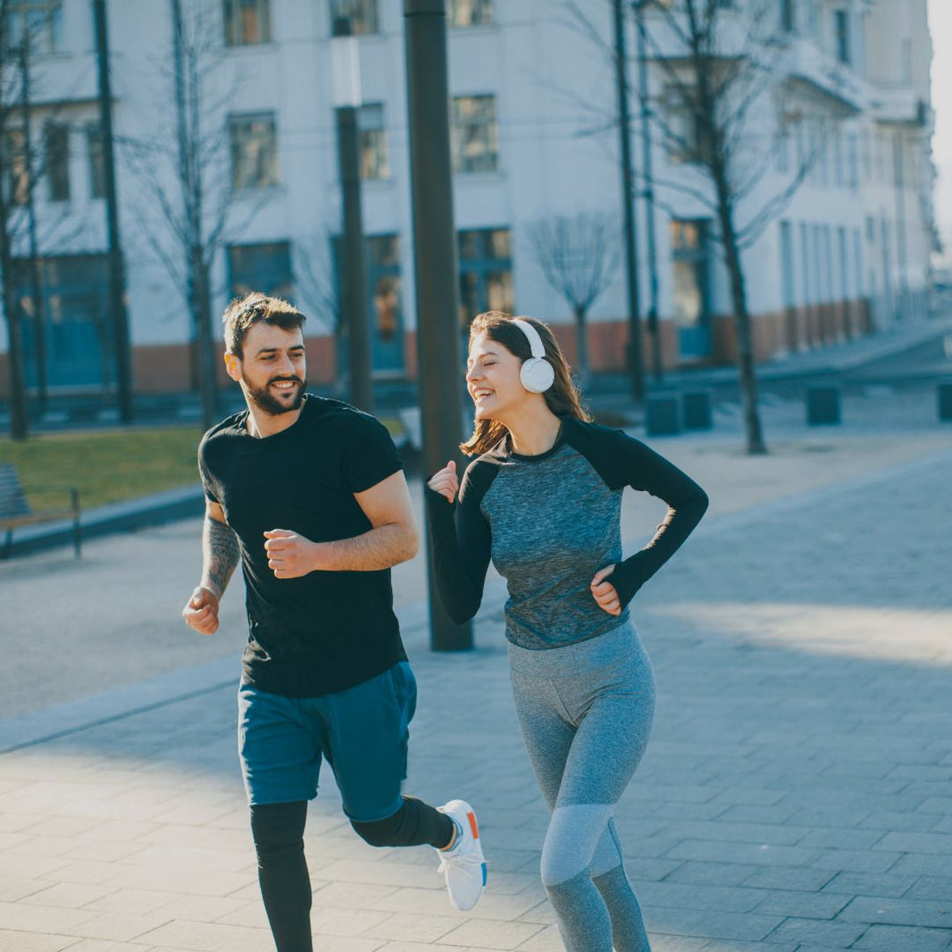 Man and woman jogging together on a city street.