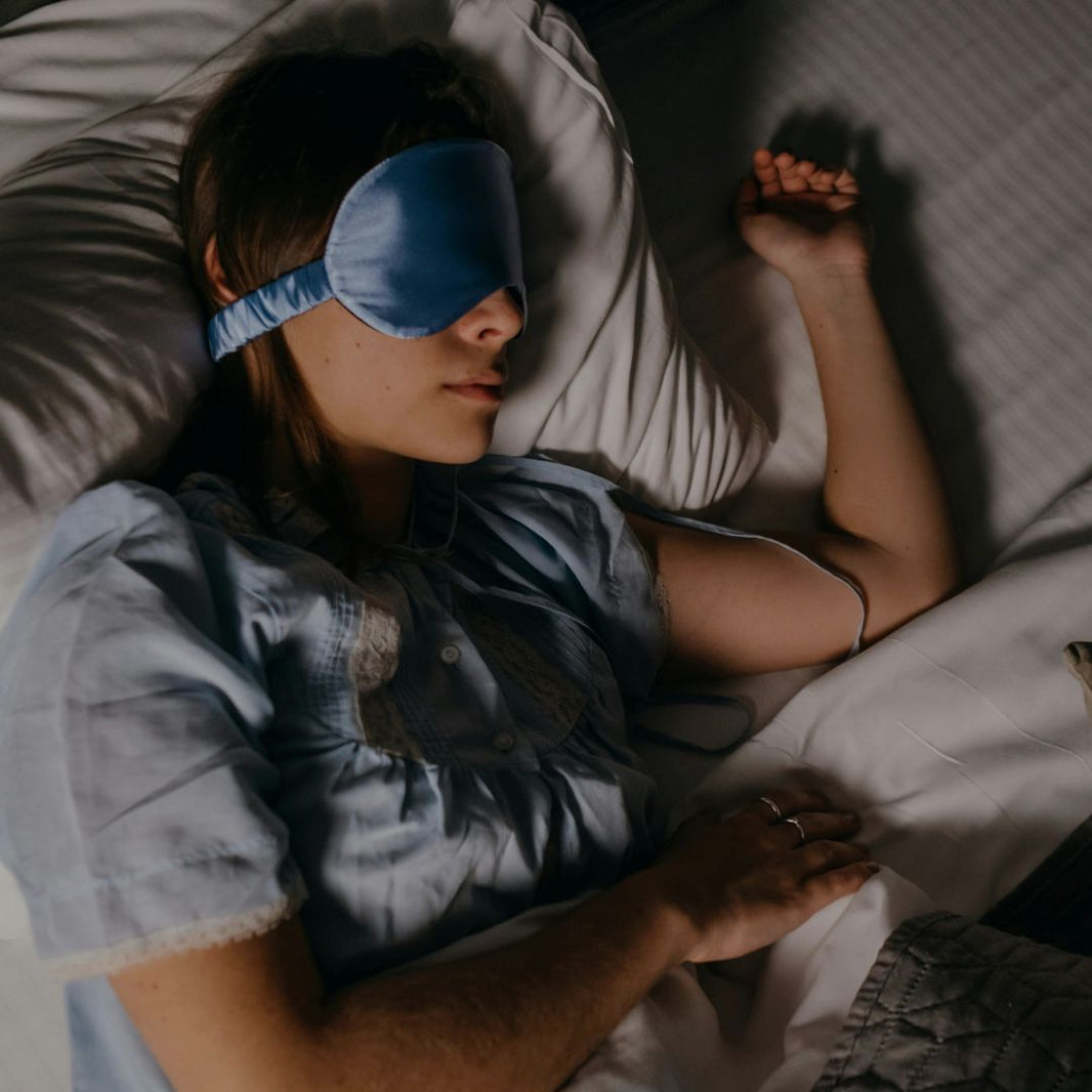 Person lying in bed wearing a blue sleep mask